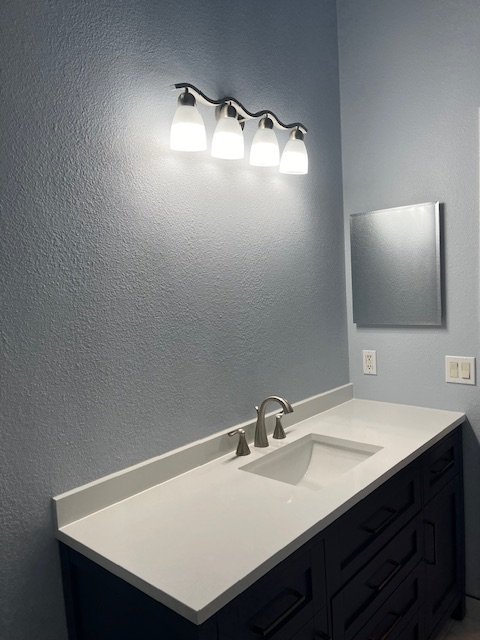 After: navy shaker vanity with white countertop, undermount sink and new light fixture