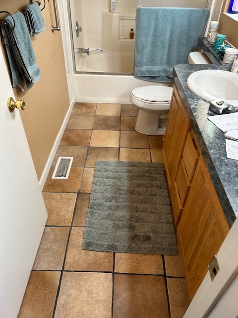Before: oak vanity with dark laminate countertop and drop-in sink